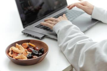 Wooden bowl with dried fruits on a white table.