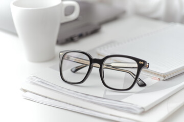 Fototapeta premium Closeup black eyeglasses on a folder with documents on desk. A female work on a background