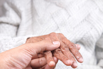 detail shot of young man holding hand of a senior women 