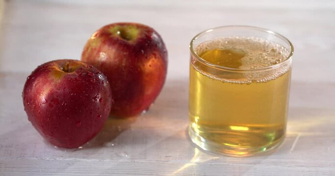 close-up of pouring juice into a glass. there are fresh red apples on the table nearby. 4k video