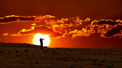 Silhouette of photographer on top of mountain at rising sun background