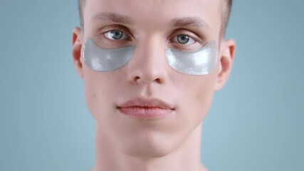 Crop view of young man with under eye patches looking to camera . Portrait of male handsome model with light blue eyes posing. Concept of skin and face care. - Powered by Adobe