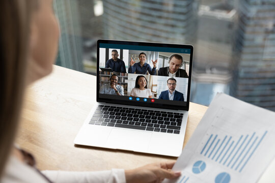 Female employee discuss paperwork with multiracial colleagues on video online call on laptop at home. Multiethnic diverse businesspeople talk speak on webcam zoom conference. Virtual event concept.