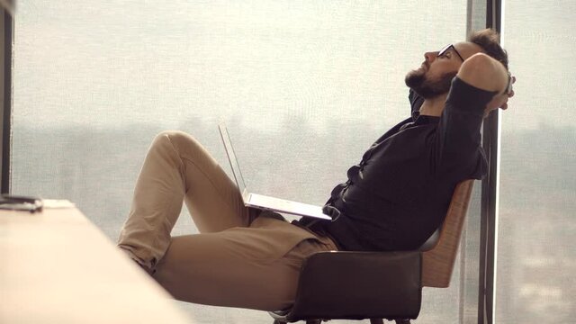 Thoughtful Serious Man Sitting On Workplace And Taking Break.Happy Healthy Stress Free Man Relaxing In Office.Employee Taking Break.Lazy Businessman Leisure In Office.Calm Mindful Peaceful Businessman