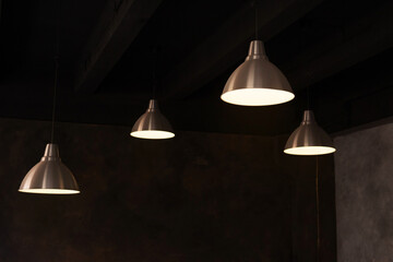 Metal simple loft-style chandeliers against a dark brown ceiling. Dark minimalistic interior.