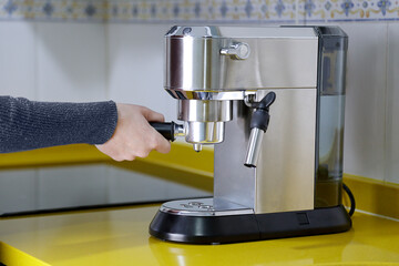 Woman placing a removable portafilter in a coffee machine to make a morning espresso. Breakfast and...