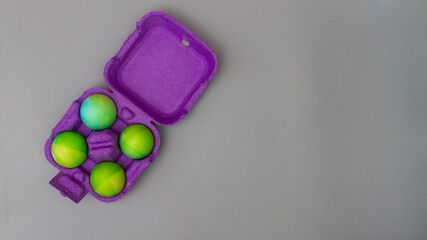 Easter eggs in a purple cardboard egg box on a gray background for the Easter holiday. Copy space