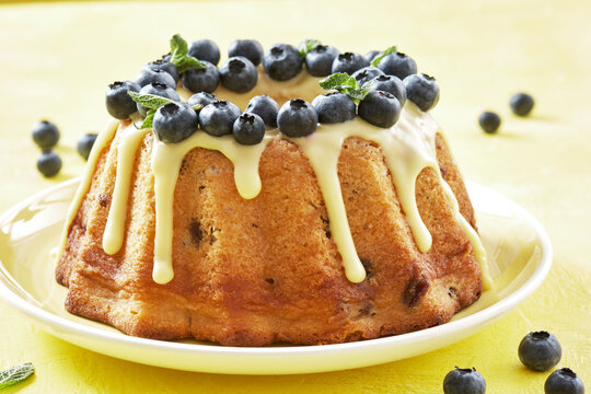 blueberry bundt cake with icing on a yellow background