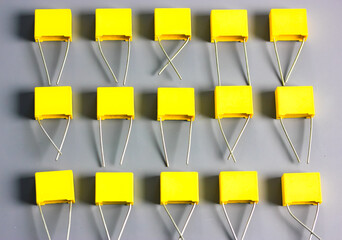 Yellow film capacitors on gray background top view. Electronic radio components.