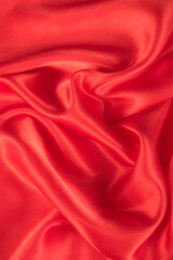 Abstract red silk fabric texture background. Cloth soft wave. Creases of satin