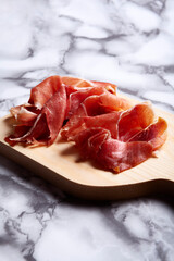 Iberian Serrano Ham tapa on cutting board with marble bottom