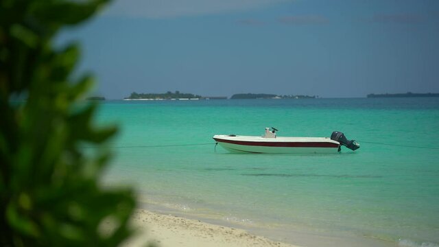 Island In Maldives - Boat Floating Over The Crystal Clear Sea Water. near the beach. Sunny day in paradise. Many island resorts on the horizontal.
