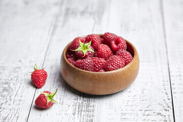 Fresh raspberries in wooden bowl on gray table. Red ripe raspberries, sweet berries