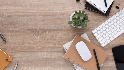 Top view wooden workspace office desk with computer and office supplies. Flat lay work table with blank notebook, keyboard, green leaf, pen and coffee cup. Copy space for your advertising content.