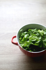 Bowl of lettuce on wooden table. Selective focus.