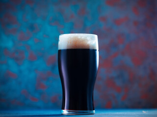 A pint glass of dark stout or porter beer on a creative colored background. Modern craft beer