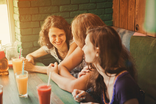 three young women sit in cafes and pizza, chat, laugh, eat pizza and drink juice. Girls are minted by glasses or glasses with drinks. A hen party with friends