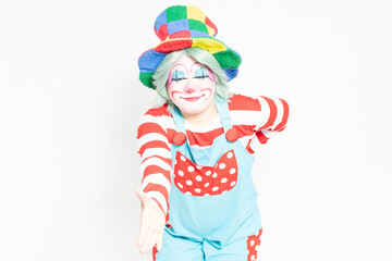 白背景の前に立って、手を差し出すジェスチャーをするピエロ