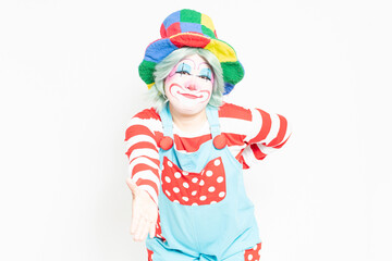 白背景の前に立って、手を差し出すジェスチャーをするピエロ