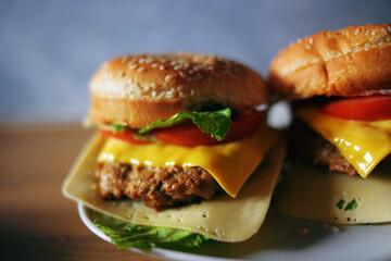 Photos of homemade burgers. Steak and white bun with sesame seeds, cheese and cabbage, tomatoes. Homemade food.
