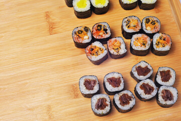 Sushi set lies on a wooden board, maki. Lots of sushi, rice, nori and filling, fish, seafood, place for food text
