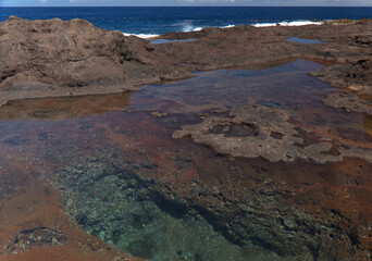 Gran Canaria, calm natural seawater pools in under the steep cliffs of the north coast, separated from the ocean by 
volcanic rock, Punta de Galdar area
