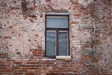 A window in a brick wall. Destroyed wall in an old building. Restoration of a historic house. A brown plastic window inserted into an old wall.
