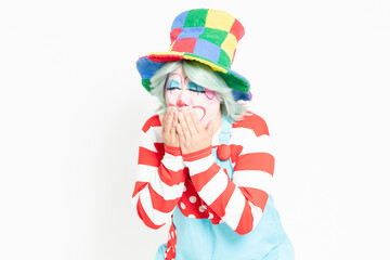 白背景の前に立って、喉が痛いジェスチャーをするピエロ