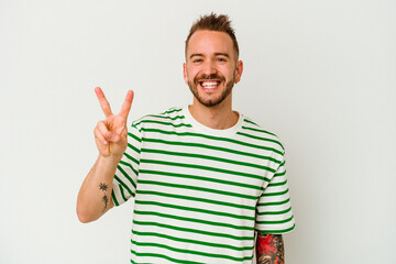 Young tattooed caucasian man isolated on white background showing number two with fingers.