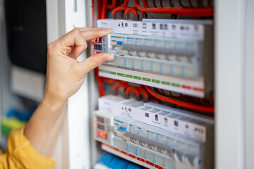 Close up on woman hand turn on the machine on the electrical panel at house. 