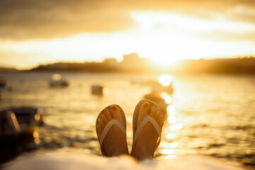 Legs of a girl against the background of the ocean and the sea, beautiful sunset and travel,...