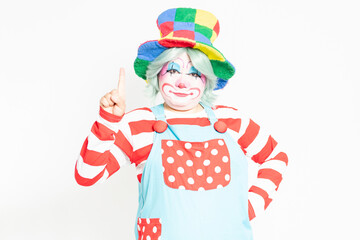 白背景の前に立って、指で数字を示すピエロ