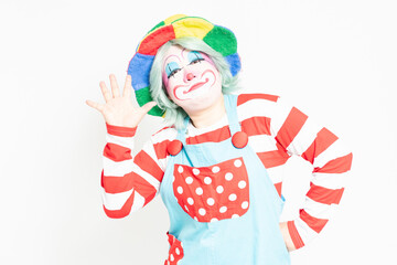 白背景の前に立って、指で数字を示すピエロ