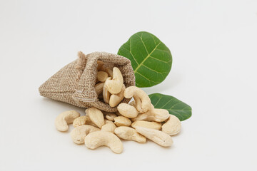 Cashew nuts with green leaf in bag isolated on white background