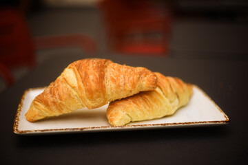 Two croissants on the table, breakfast outside in a restaurant. French building