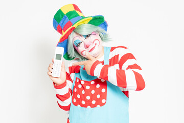 白背景の前に立って、電話を使うピエロ