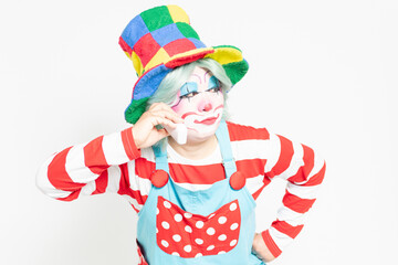 白背景の前に立って、電話を使うピエロ