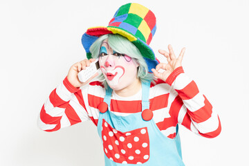 白背景の前に立って、電話を使うピエロ