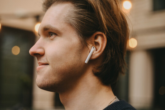 Man in wireless headphones outdoor, street, restaurant. Man listening to e-book, the guy is listening to music. A man in bluetooth headphones is enjoying life.