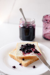 Berry jam spreading on toast with a knife. The concept of morning breakfast and home comfort. top view