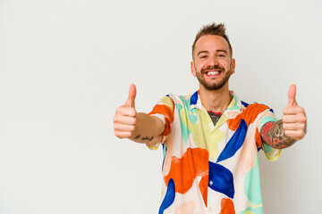 Young tattooed caucasian man isolated on white background smiling and raising thumb up