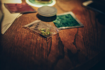 Grinder and marijuana lies on the table, drugs in Amsterdam. Mushrooms and herbs on a wooden table. Light drugs on the road in a zip package.
