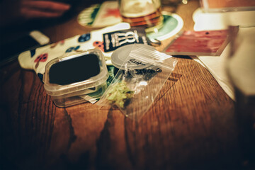 Grinder and marijuana lies on the table, drugs in Amsterdam. Mushrooms and herbs on a wooden table. Light drugs on the road in a zip package.