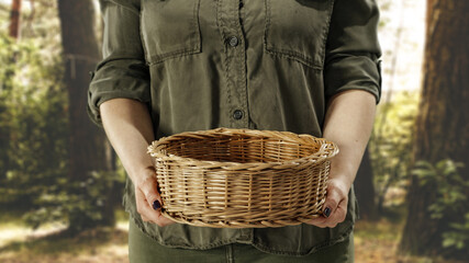 Empty basket in woman hands and forest background 