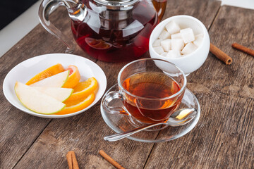 Teapot and cup set with sliced fruits and sugar on the wooden table