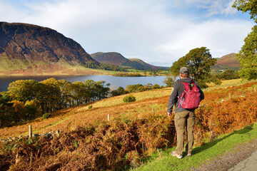 Fototapeta premium Male tourist enjoying the view of Crummock Water lake, located between Loweswater and Buttermere, in the Lake District in Cumbria, North West England.