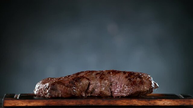Flying piece of grilled beef steak falling on table. Filmed on high speed cinema camera, 1000 fps.