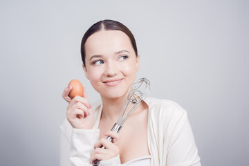 The girl stands in white background, balloon whisk and aggs and cooks, cooking courses, school...