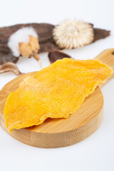 dried mango, sugar-free, on a wooden board, on a white background