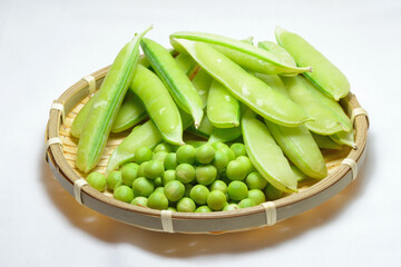 ざるに入ったグリンピースのさやと中身